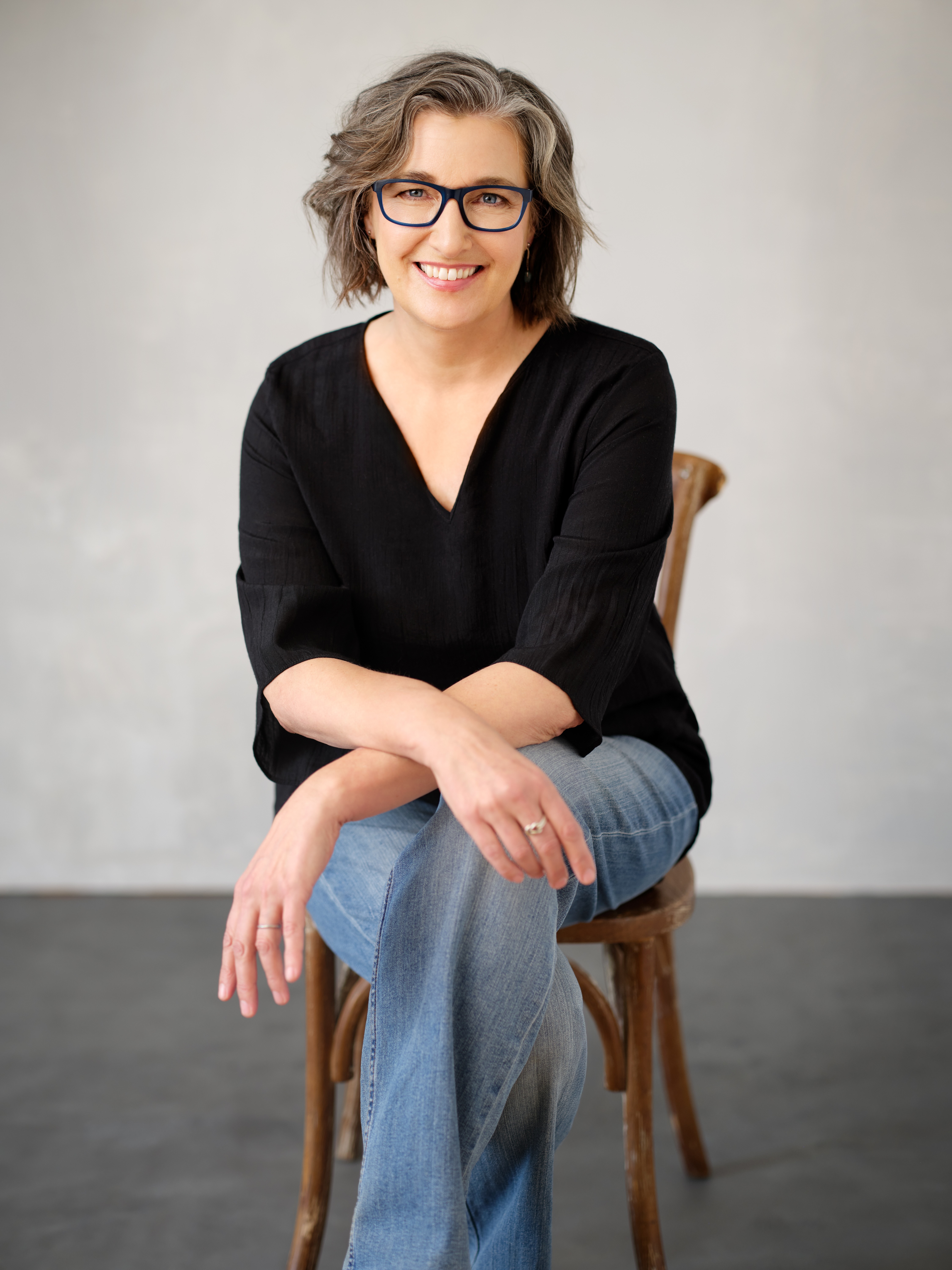 Joanne, sitting on a chair, smiling warmly at the camera